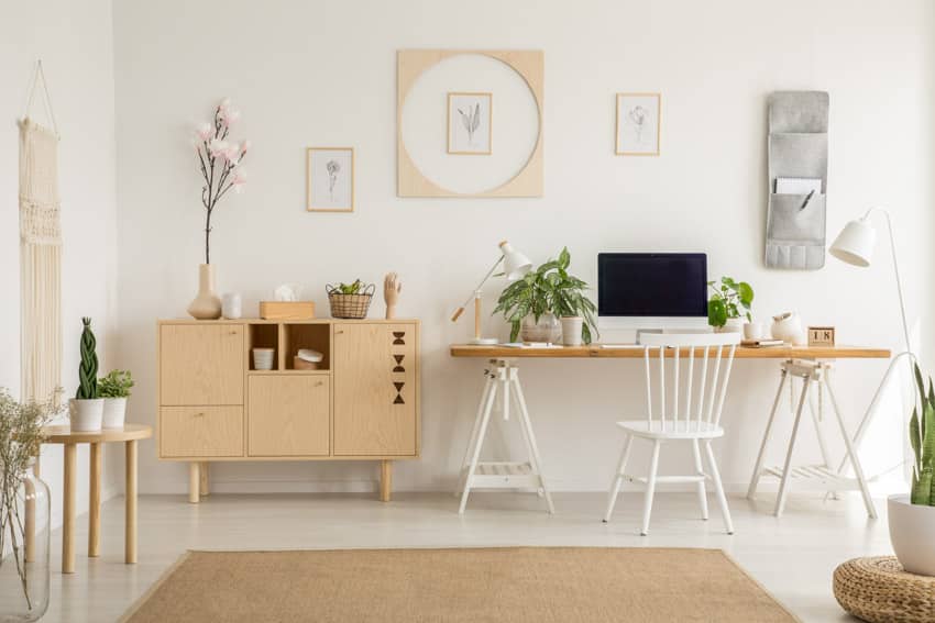 Oficina en el hogar de inspiración bohemia con decoración de pared, mesa, silla, alfombra y plantas de interior