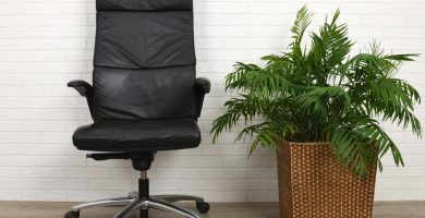 Cómoda silla de oficina negra contra pared de ladrillo blanco y suelo gris