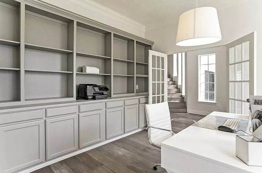 Oficina en el hogar con armario empotrado gris, escritorio blanco y puertas francesas