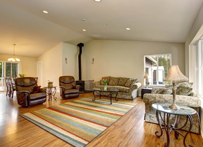 Sala de estar con sillones reclinables de cuero marrón alfombra colorida lámpara de mesa paredes blancas