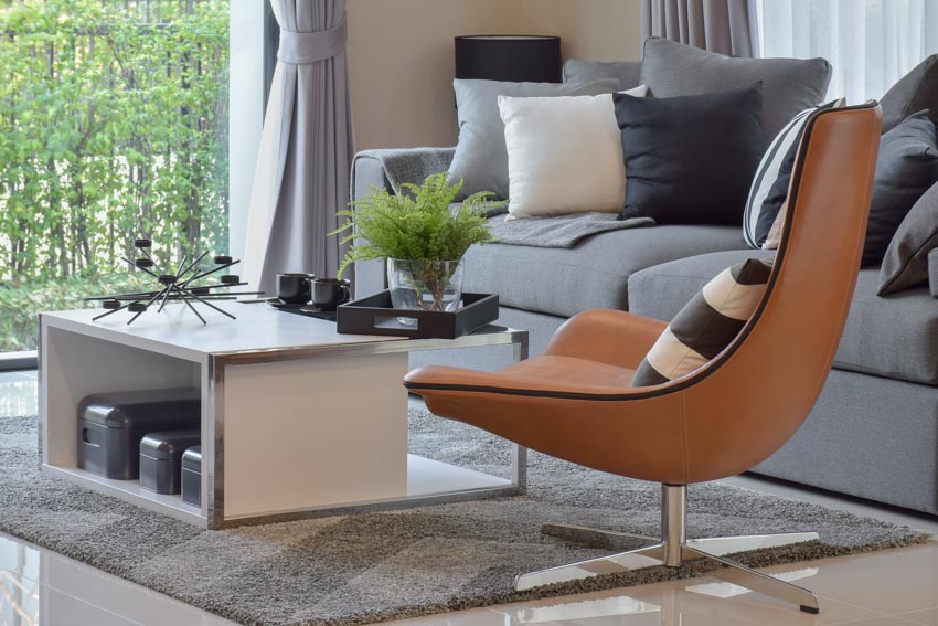 Sala de estar con silla decorativa giratoria, sofá, alfombra, mesa pequeña y cojín