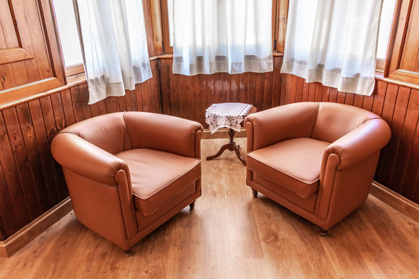 Sala de estar con sillas decorativas, cortinas en las ventanas y pisos de madera