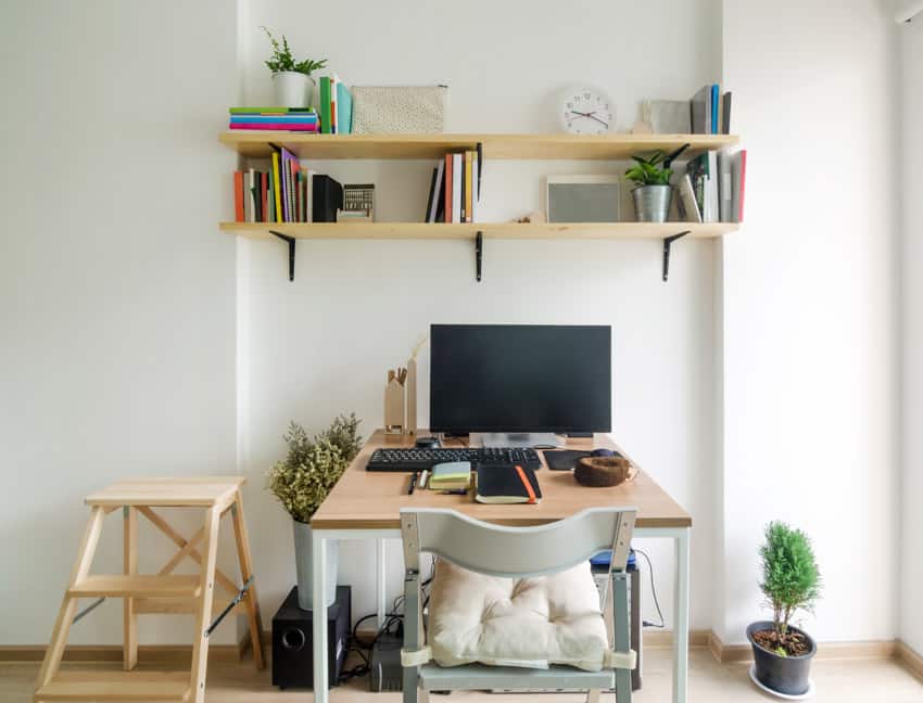 Configuración simple de oficina en el hogar con estantes flotantes, computadora, mesa y silla
