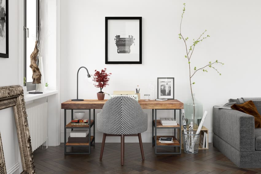 Configuración sencilla de oficina en el hogar con decoración de pared, mesa, silla, ventana, sofá y piso de madera oscura