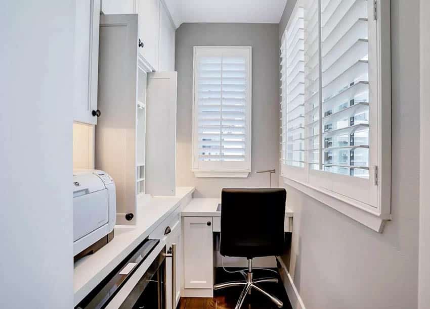 Small home office with built in desk white cabinets plantation shutters