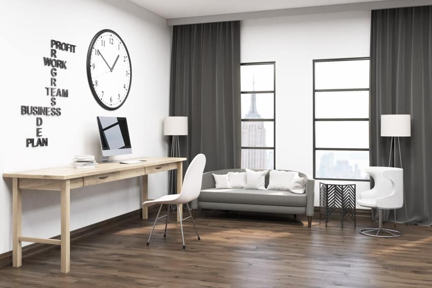 Espaciosa oficina en el hogar con reloj de pared, piso de madera, mesa, silla y sofá
