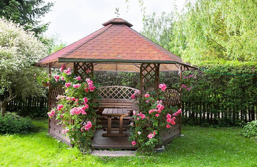 Cenador de madera con banco de mesa de madera de rosas rosadas